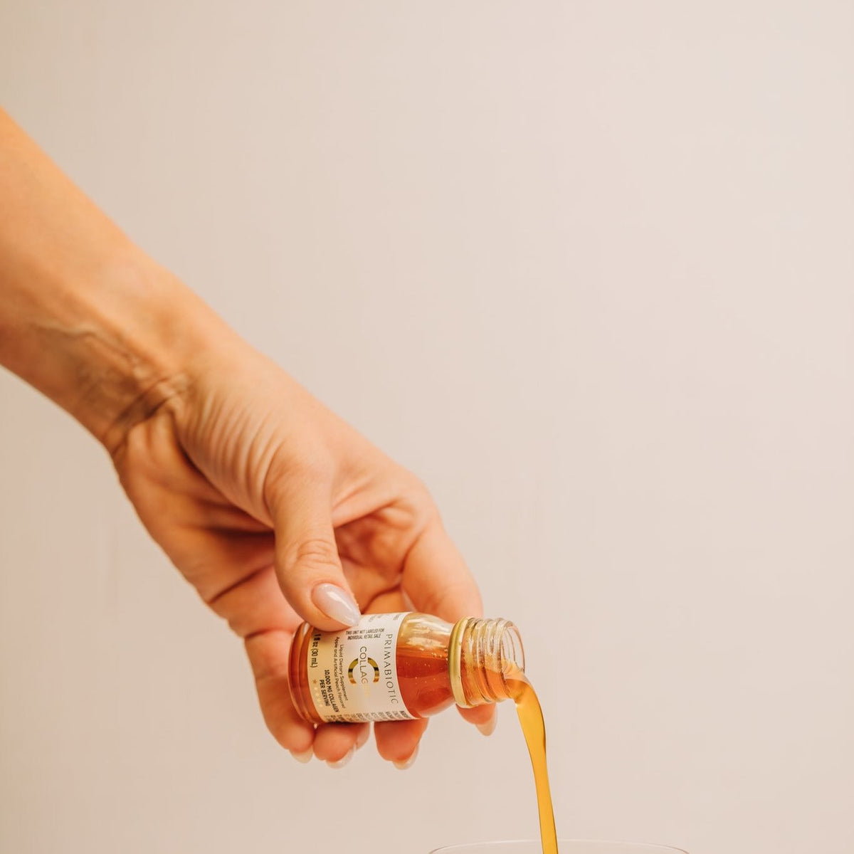 Hand pouring a bovine collagen shot into a glass