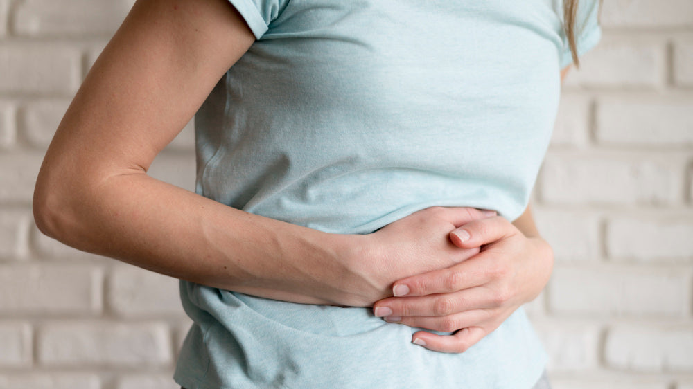 Person holding stomach due to bloating after eating