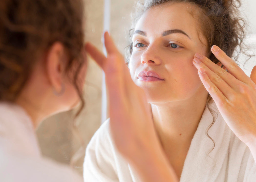 Woman checking dehydrated skin in bathroom mirror