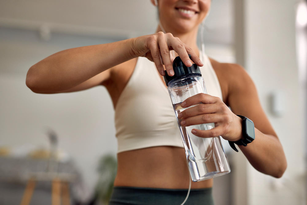 Woman in workout clothes opening a water bottle