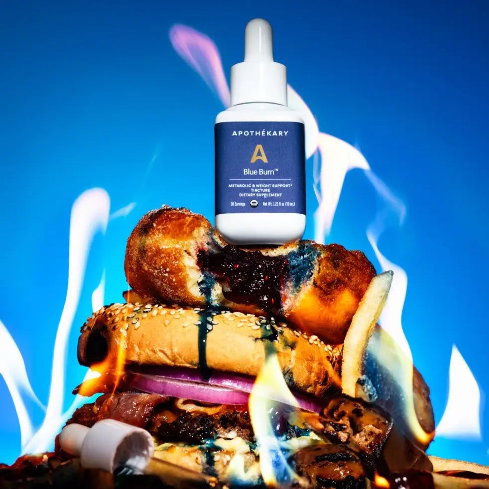 Apothékary Blue Burn Tincture bottle displayed on top of junk foods to illustrate metabolic support