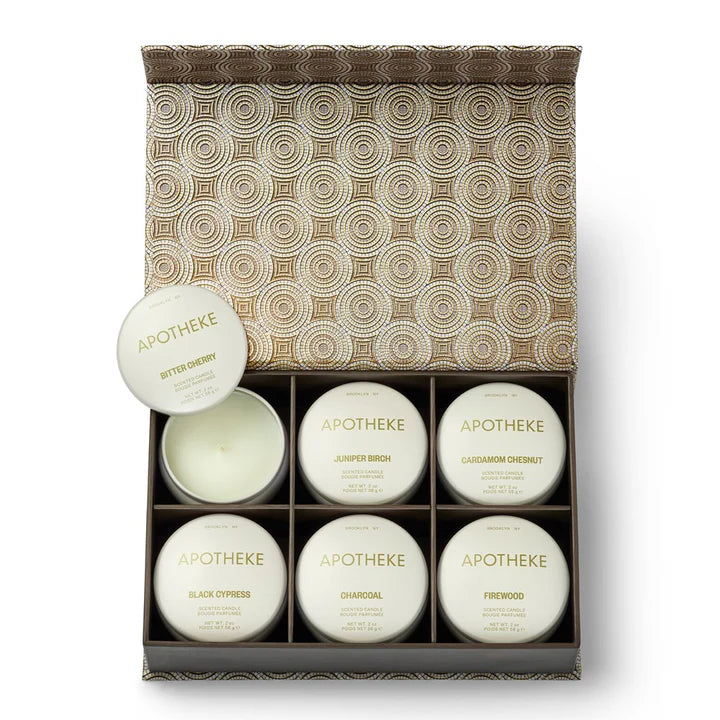 A set of white candle jars and two round lids arranged in front of a decorative patterned box