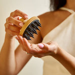 Person holding a scalp massager with a neutral background
