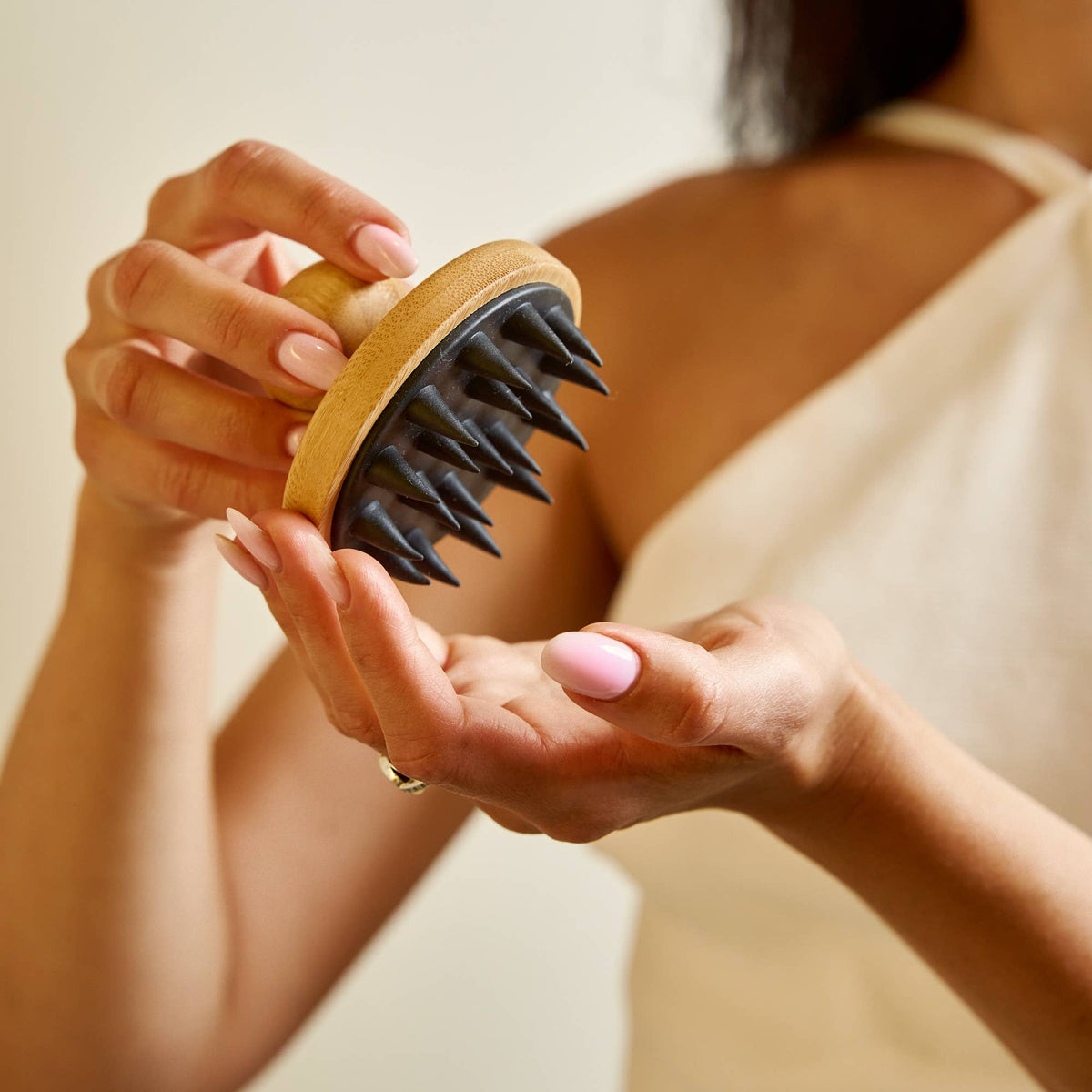 Person holding a scalp massager with a neutral background