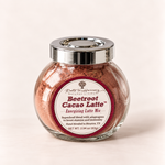 A glass jar of Beetroot Cacao Latte mix by Roots in Harmony Natural Living, featuring a silver lid and a white label with red accents, set against a plain off-white background.