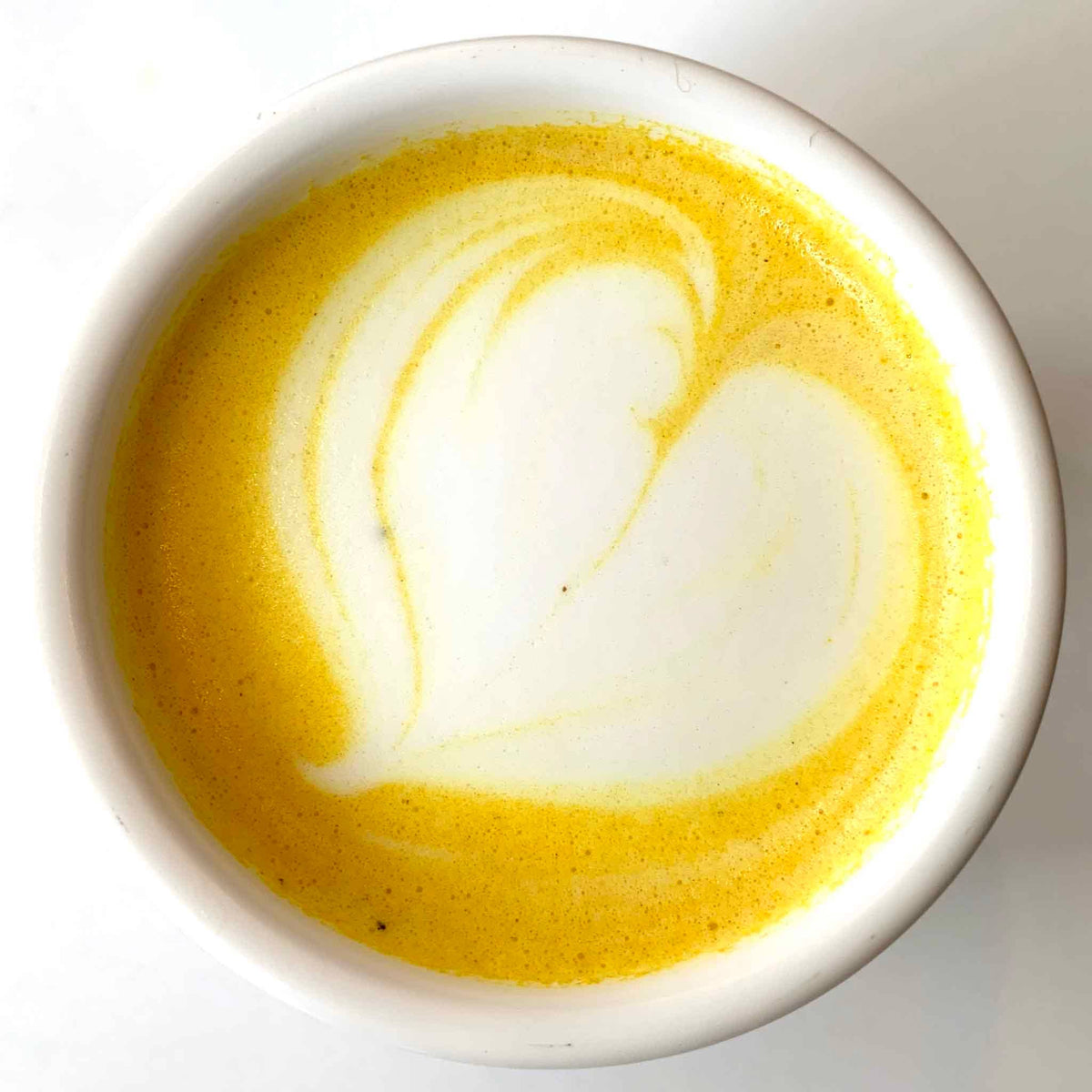 Yellow and white latte art in a white cup on a white background