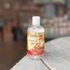 Good Life Box by Campus Rebel - Surfs Up Coconut Lime Body Wash clear bottle with tropical floral label on a wooden surface in a boutique store setting
