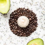 A small round jar of white cream or balm sits in the center of a ring of roasted coffee beans