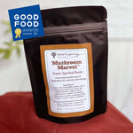 A stand-up pouch of Mushroom Marvel Organic Superfood Powder by Roots to Harmony Natural Living, shown on a red fabric surface with a blue Good Food Awards 2026 badge in the top left corner.