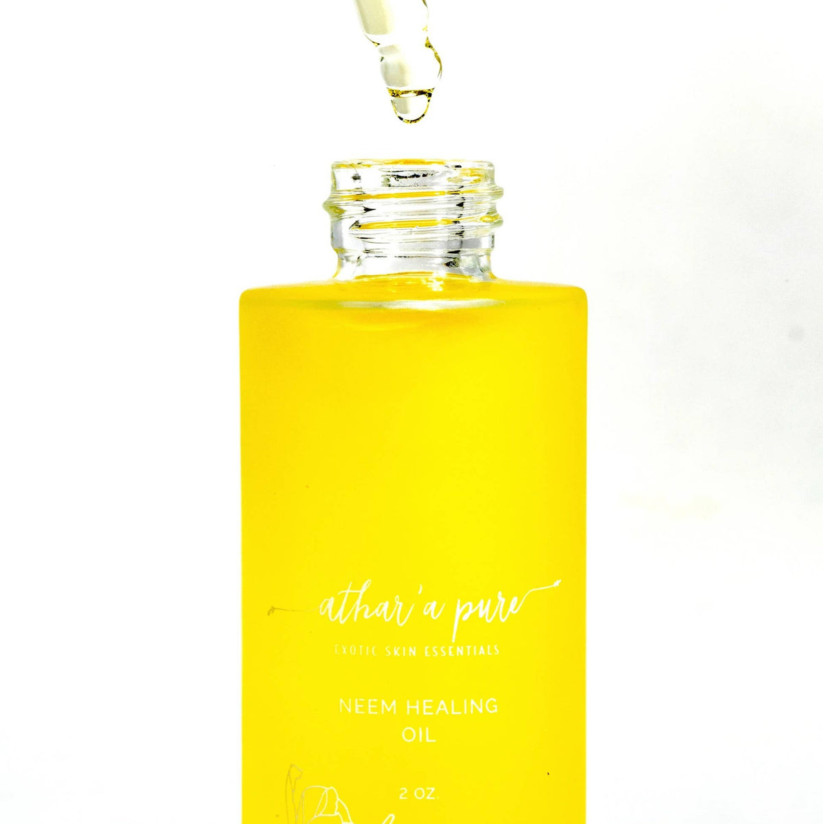 A bottle of Athar'a Pure Neem Healing Oil filled with bright yellow liquid, shown with a glass dropper above the open bottle