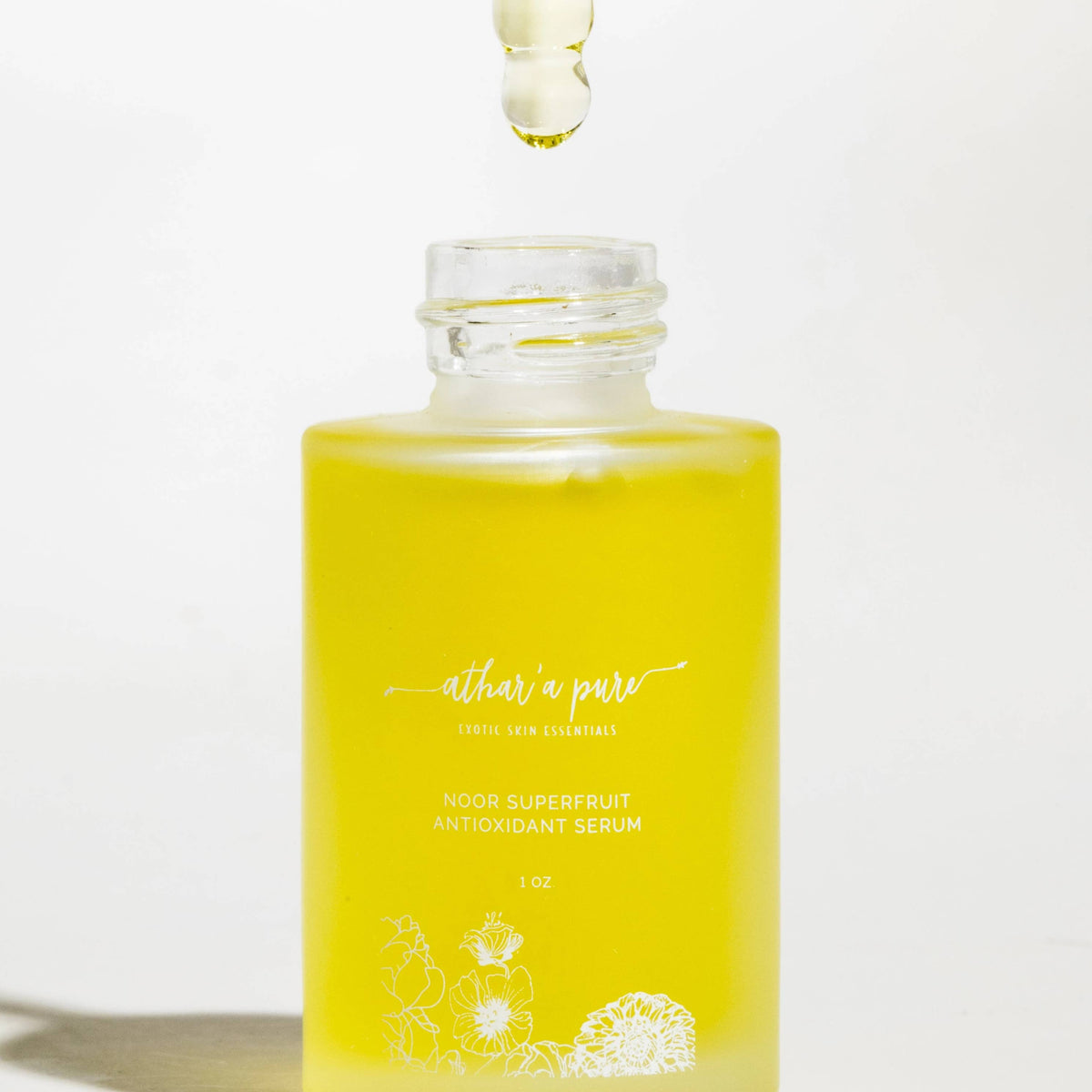 A glass dropper bottle of Nourish & Pure Rose Superfruit Antioxidant Serum filled with bright yellow liquid