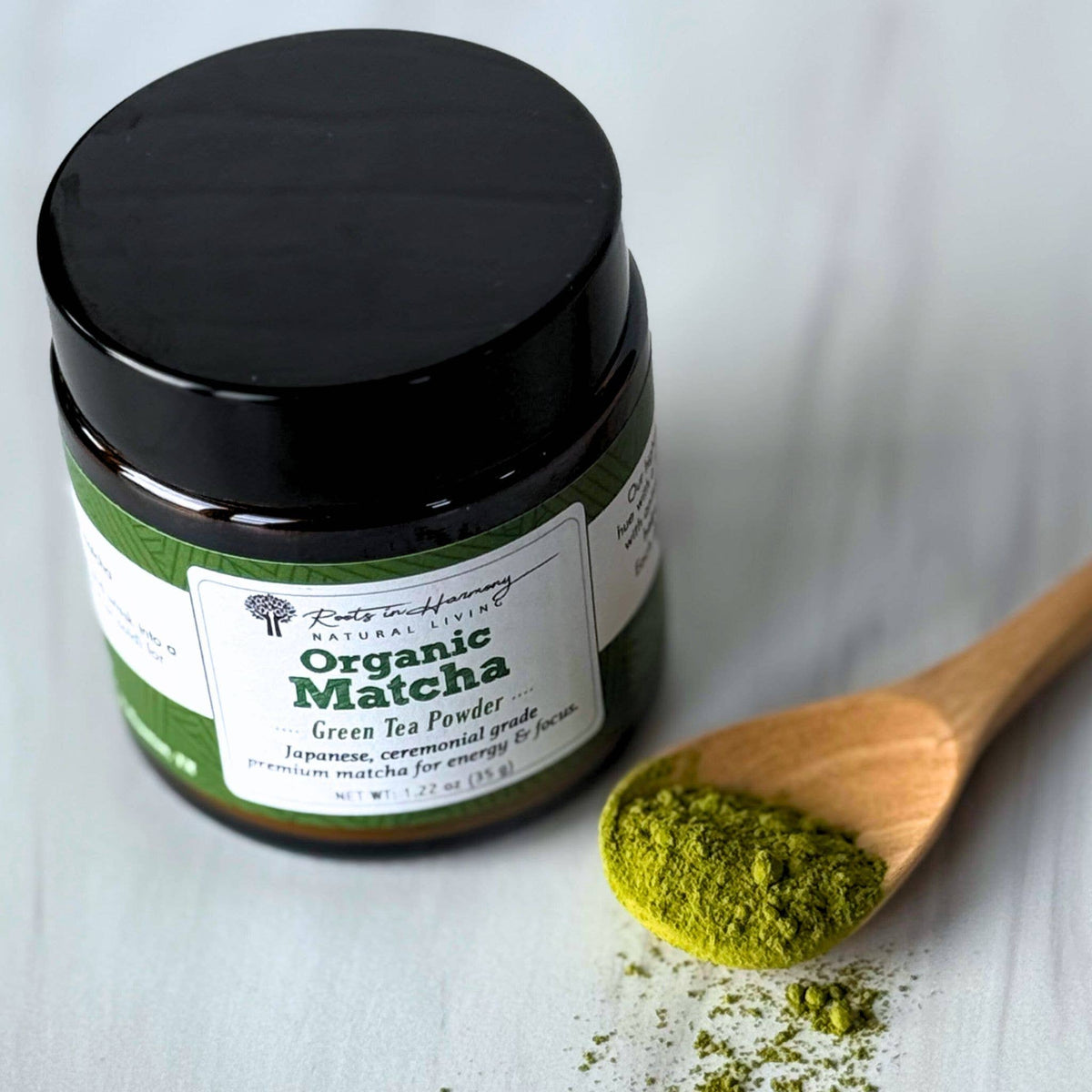 Jar of Organic Matcha green tea powder with a wooden spoonful of powder on a light background