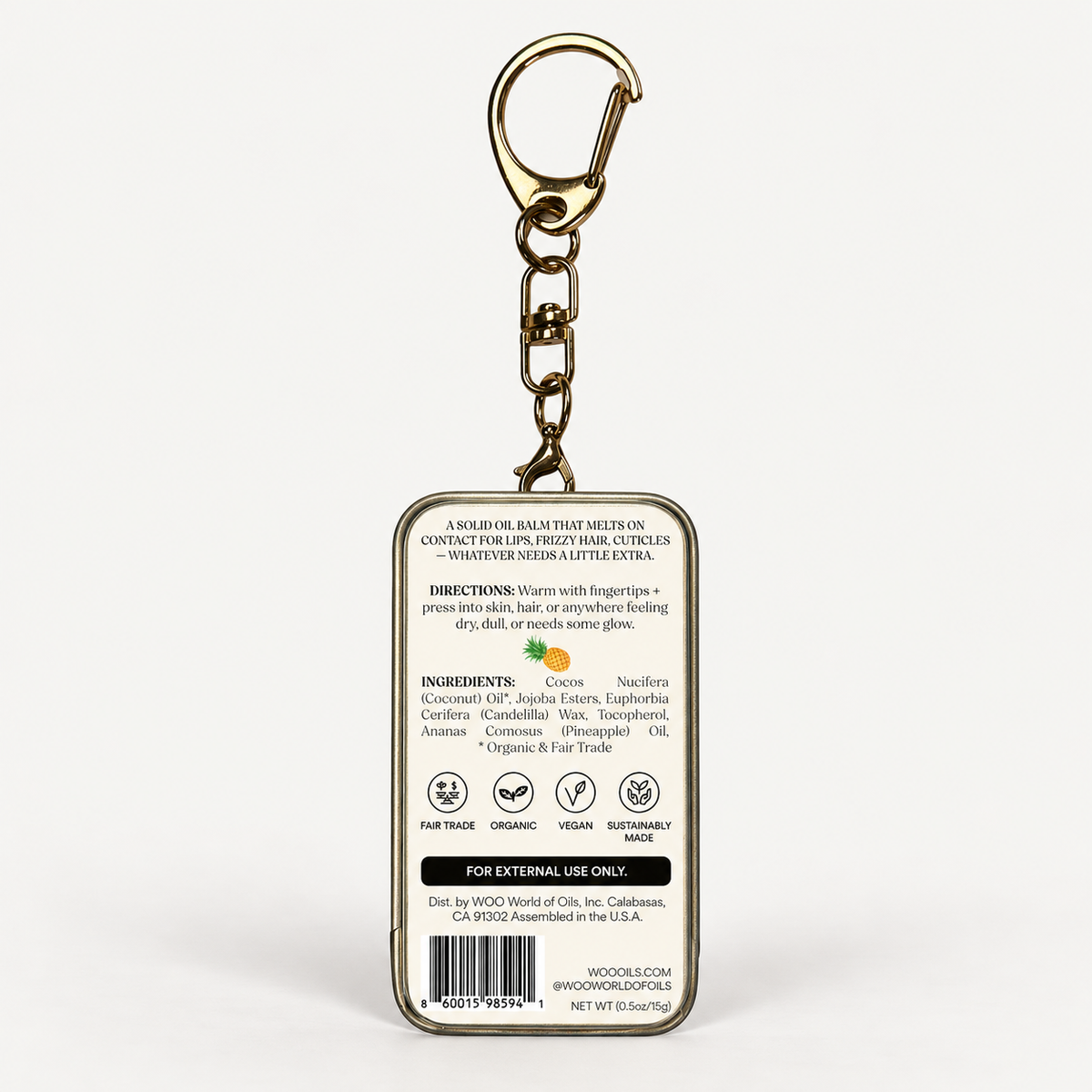 A square metal keychain container shown from the back, featuring a gold-tone keyring and clasp, with printed product information including ingredients, direction, icons, and a barcode on a white background.