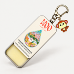 A metal tin of NOO brand Pineapple Solid Oil Balm with a keychain attachment featuring a monkey charm, shown on a clean white background.