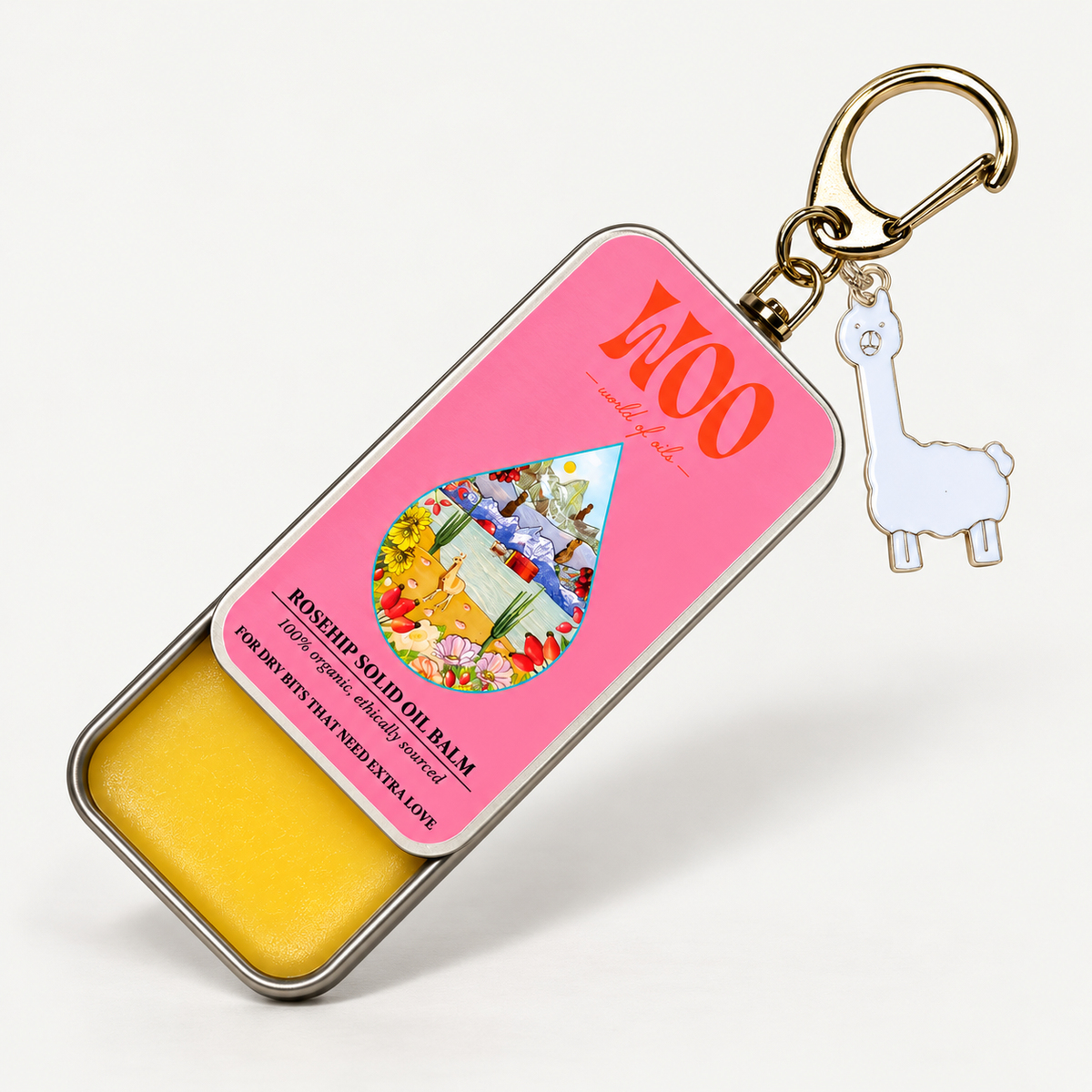 A rosehip solid oil balm keychain tin by woo, featuring a bright pink label with orange lettering, a clear window showing yellow balm inside, and a white llama charm attached to a gold keyring.