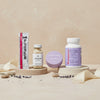 The Menopause Kit featuring Superieur supplement strips, Apotheke Ashwagandika tincture, Honey Lavender balm tin, and Womaness Me No Pause vitamins on circular platforms with lavender flowers