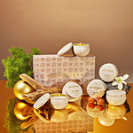 A set of white candle jars and two round lids arranged in front of a decorative patterned box