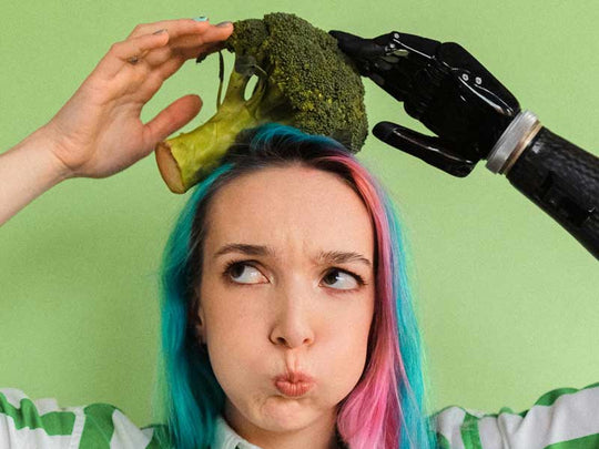 Person with rainbow colored hair holds broccolie onto their head.