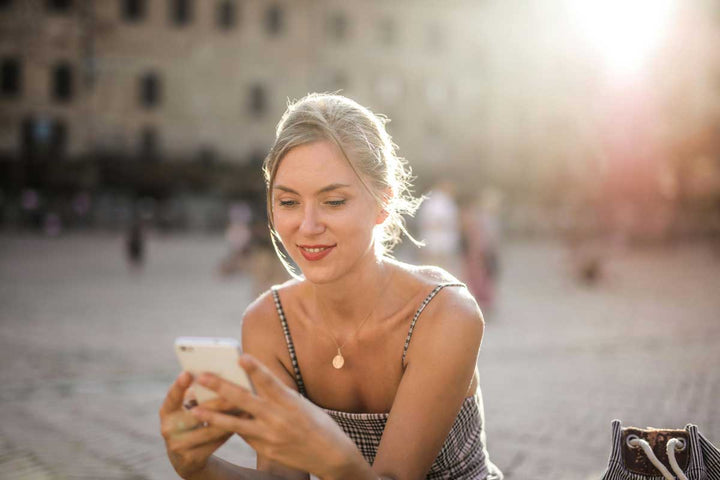 Smiling woman looks on at her cellphone.