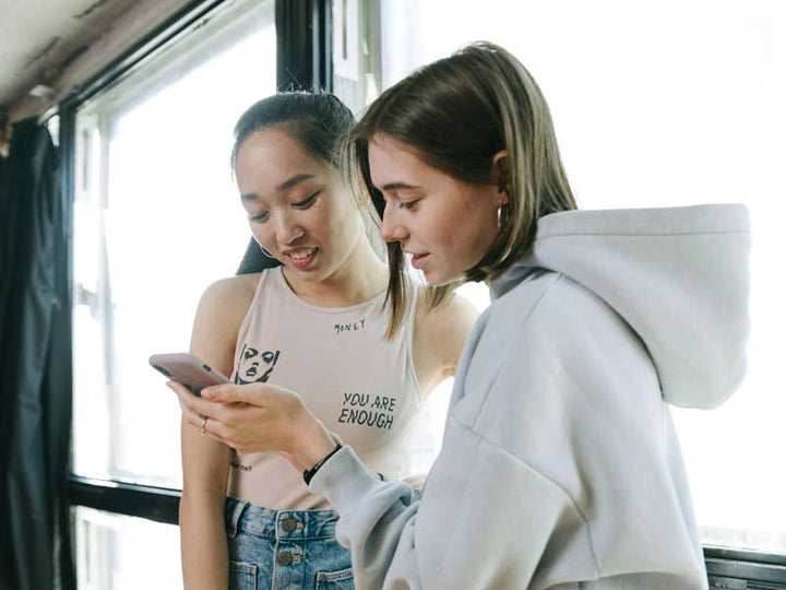 Two people look at a single cellphone.