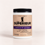 A white plastic jar of drink SUPERIEUR [electrolytes] Concord Grape flavor, featuring a kraft paper label with a purple band 