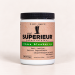 A white plastic tub of drink SUPERIEUR electrolytes in lime blueberry flavor, featuring a black ribbed lid and a tan label with green and black text, set against a plain off-white background.
